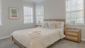 A bedroom with a large bed, two bedside tables, and a nightstand. - MidTown Flats Suite C1 (Columbus)