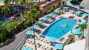 A resort with multiple swimming pools, lounge areas, and palm trees. - Steps to Beach  Resort Amenities  Kitchen (Honolulu)