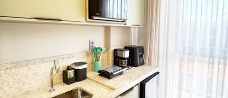 A modern kitchen with a built-in microwave, a coffee maker, and a sink.