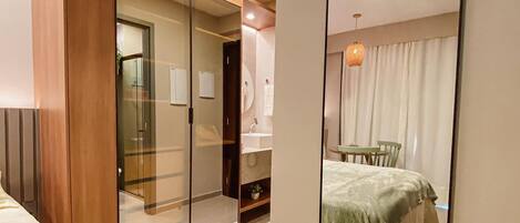 A bedroom with a bed, a wardrobe, a mirror, and a small table with chairs.