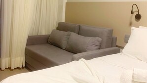 Una habitación de hotel con una cama, un sofá y una mesita de noche.