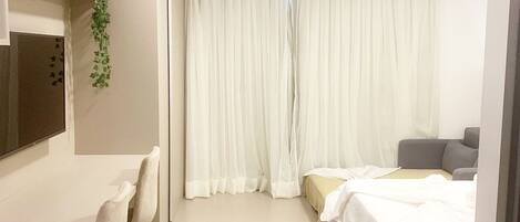 A hotel room with a bed, a desk, a chair, a television, and a window with curtains.