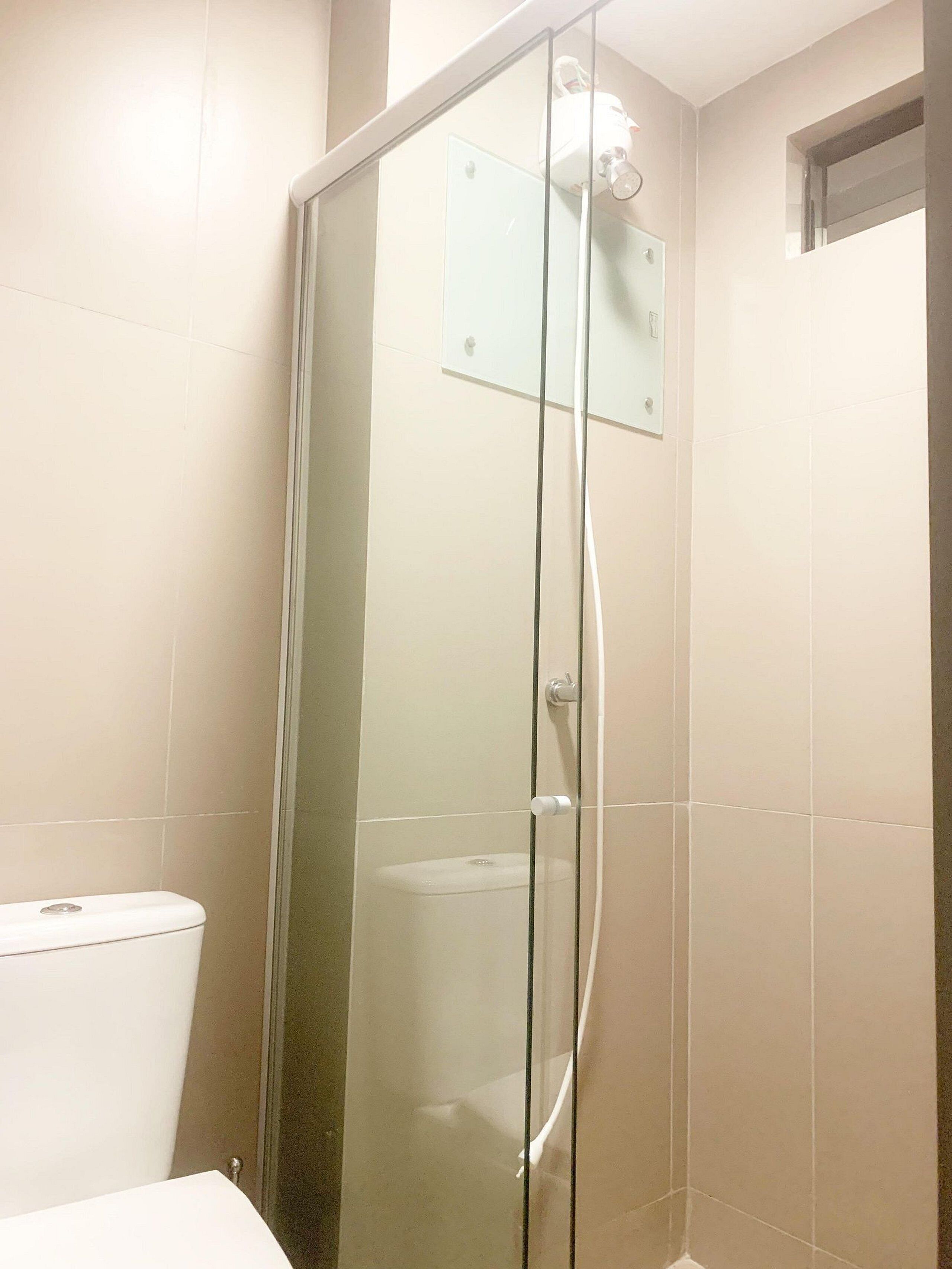 Un vestidor de ducha con paredes de vidrio, con un inodoro blanco visible a la izquierda.