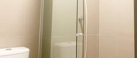 Un vestidor de ducha con paredes de vidrio, con un inodoro blanco visible a la izquierda.