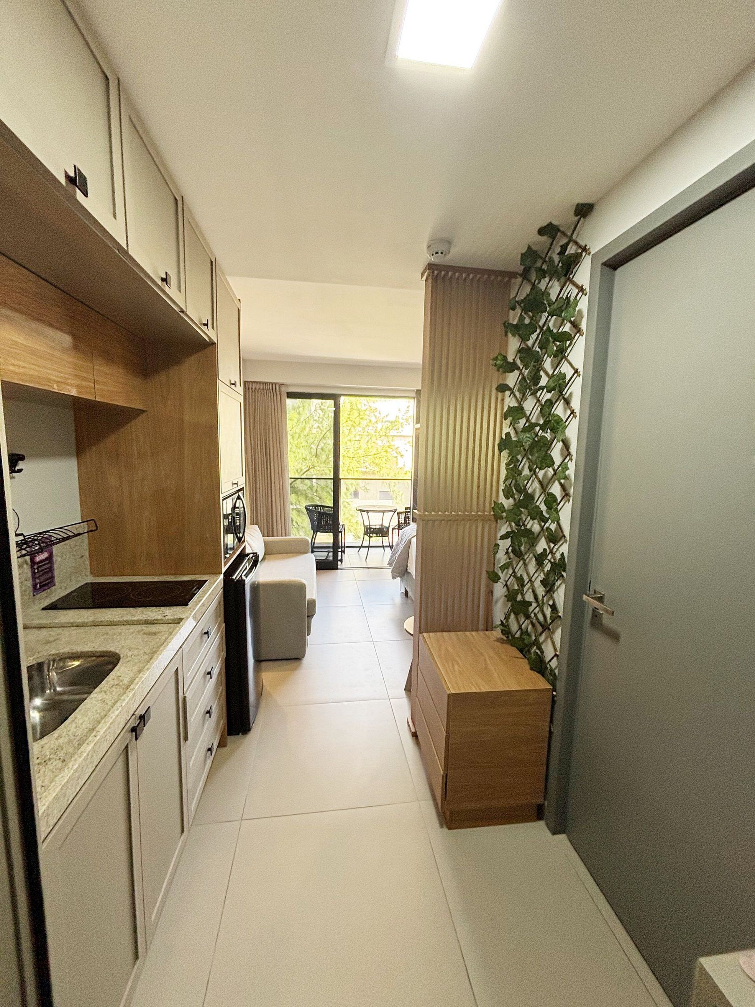 Cocina compacta con lavamanos, armarios y comedor con mesa y sillas.
