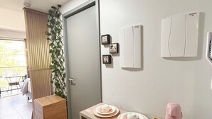 Una cocina compacta con una mesa de madera, un cubo de basura y una puerta que da a un balcón.