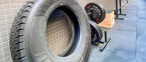 A building with a tiled exterior, a large tire, and weightlifting equipment.