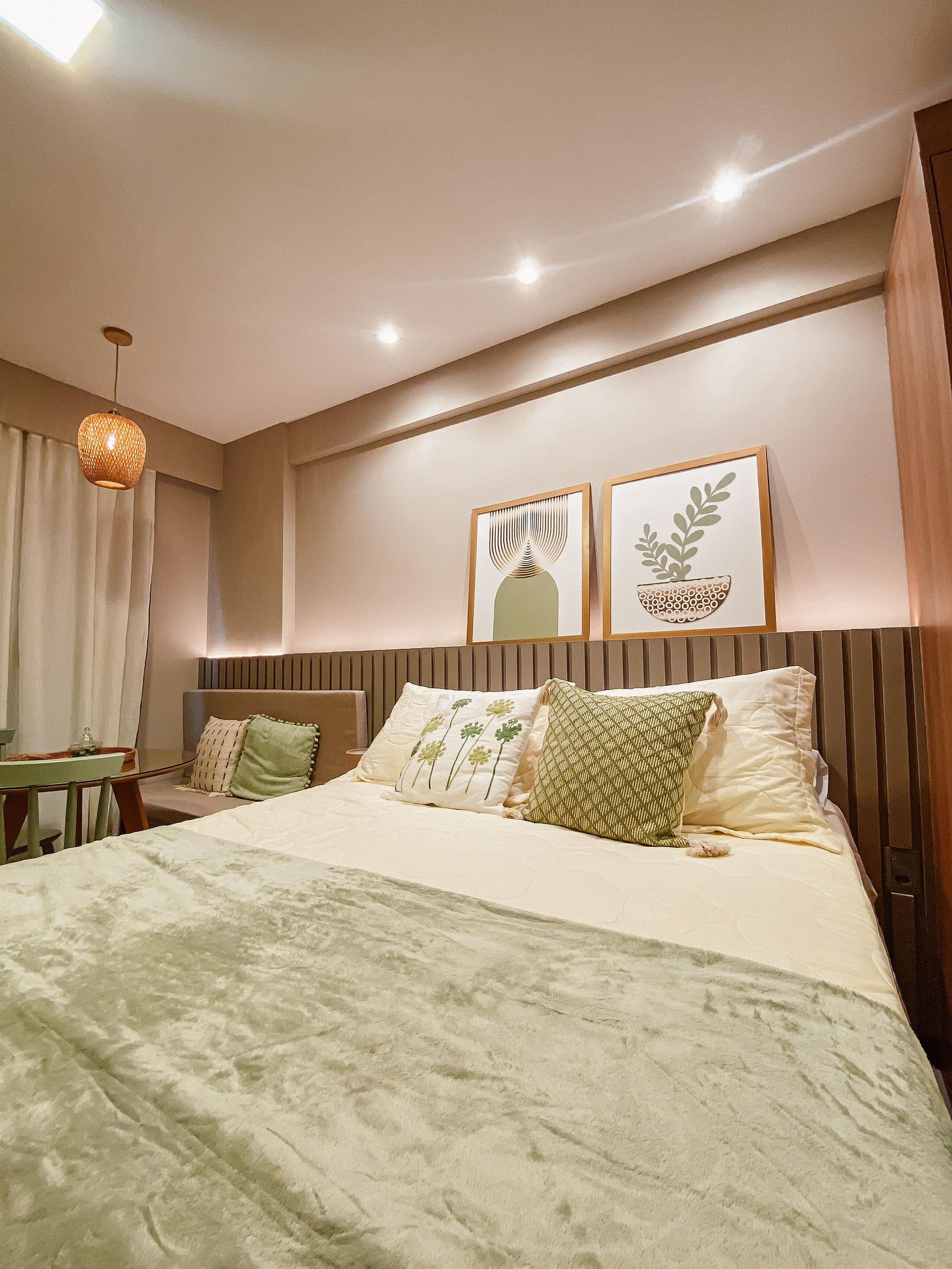 Une chambre d’hôtel avec un lit, une table de chevet, une lampe et deux œuvres d’art encadrées accrochées au mur.