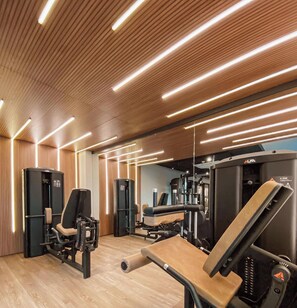 A gym with exercise equipment, wooden panel walls, and modern lighting. - Beach Haus by Day by Day (Joao Pessoa)