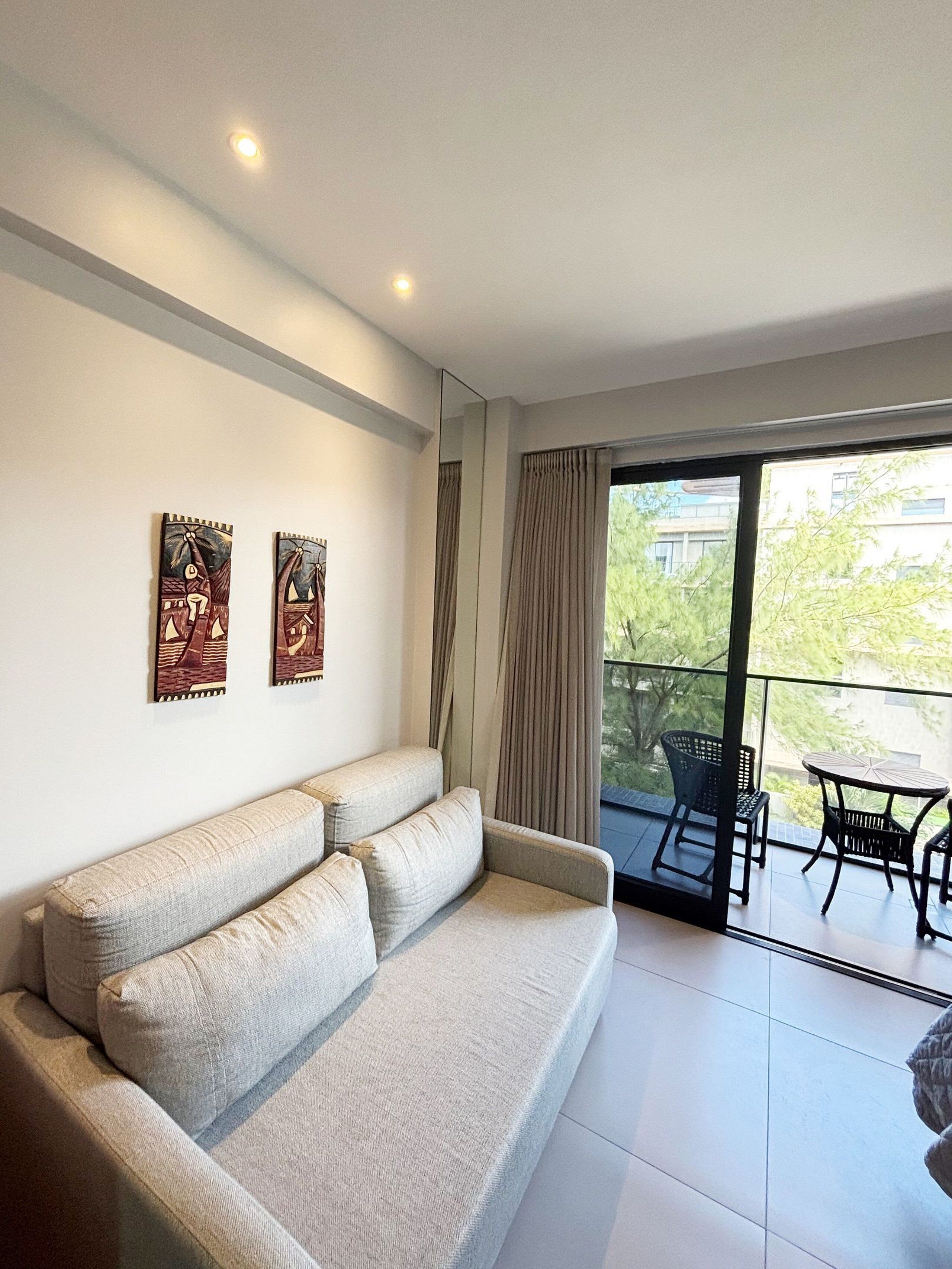 Ein modernes Wohnzimmer mit einer Couch, einem Esstisch mit Stühlen und einem Balkon mit Blick.