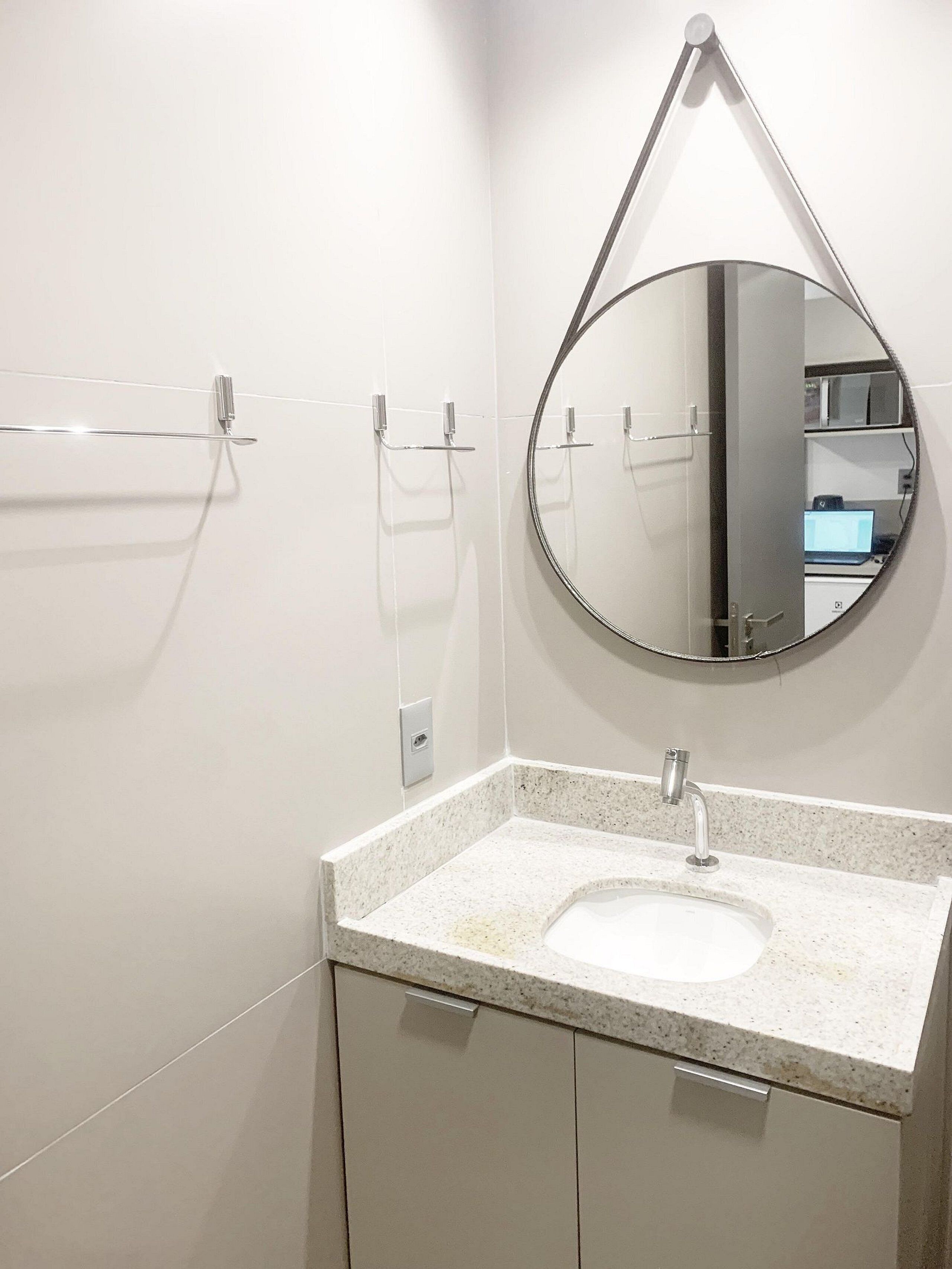 A bathroom with a white sink, a mirror, and a towel rack.