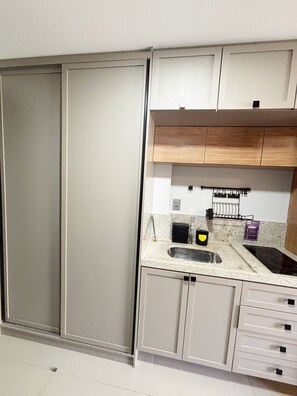 Una cocina con un lavabo, estufa, armarios y una puerta corredera.