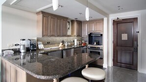 Une cuisine moderne dotée de plans de travail en granit, d’appareils électroménagers en acier inoxydable et d’armoires en bois.