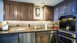 Une cuisine moderne avec des meubles en bois foncé, un plan de travail en granit, des appareils électroménagers en acier inoxydable et un dosseret carrelé.