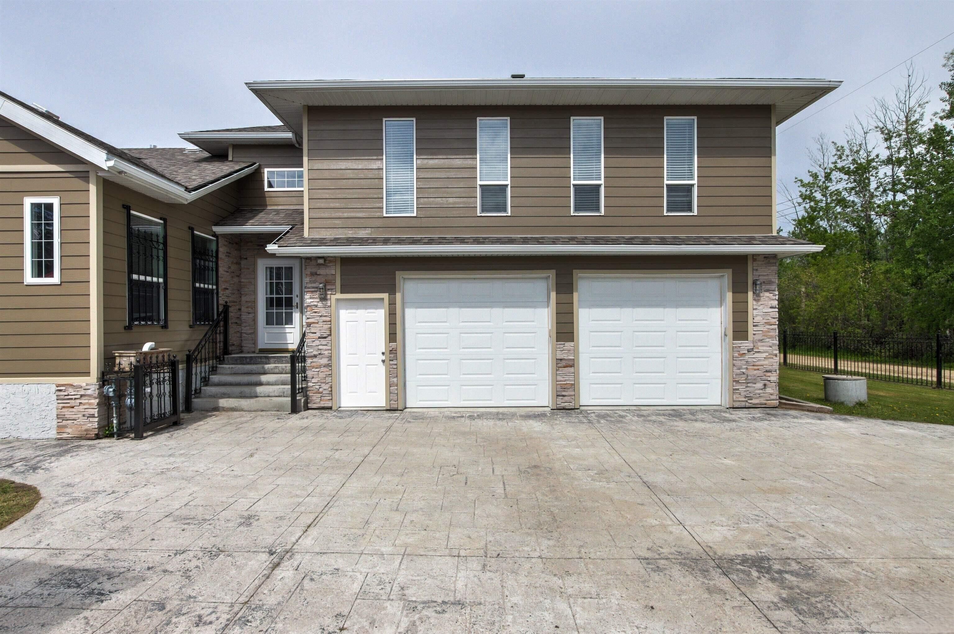 A two-story house with a garage, stone accents, and a concrete driveway.