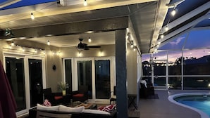 An outdoor patio area with a pool, seating, and string lights.