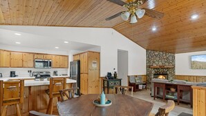 A spacious kitchen with wooden cabinets, a dining table, and a stone fireplace.