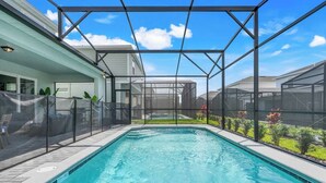 A swimming pool with a glass enclosure, surrounded by a landscaped garden and a modern building structure.