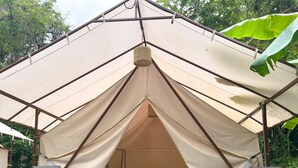 Tienda de campaña con una cama y dos sillas en su interior.