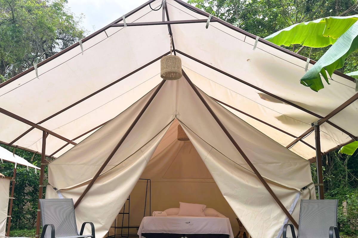 A tent with a bed and two chairs inside.