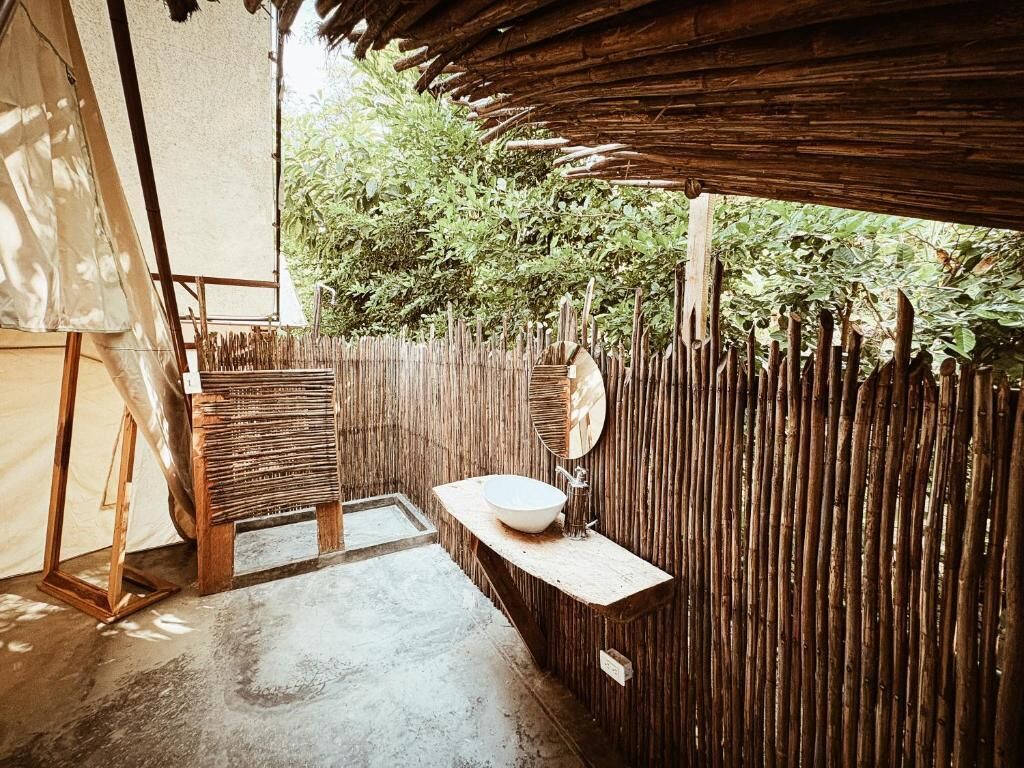 A rustic bathroom with a wooden bench, a sink, and a mirror.