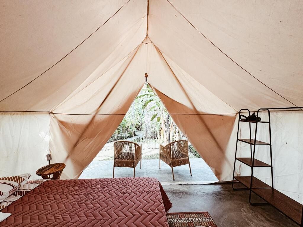 Una carpa con una cama, dos sillas y un estante.