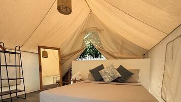 A tent with a bed, a hanging light fixture, and a patterned rug.