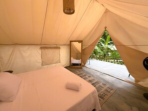 A tent-style room with a bed, a hanging light fixture, and a view of greenery outside. - Glamping Kunna Tayrona (Santa Marta)