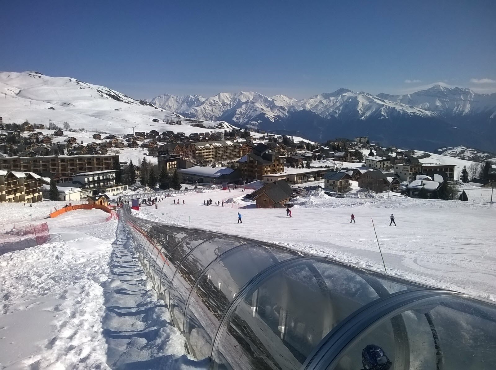 Un centro de esquí con un extenso complejo de edificios, pistas cubiertas de nieve y una vista despejada de montañas distantes.