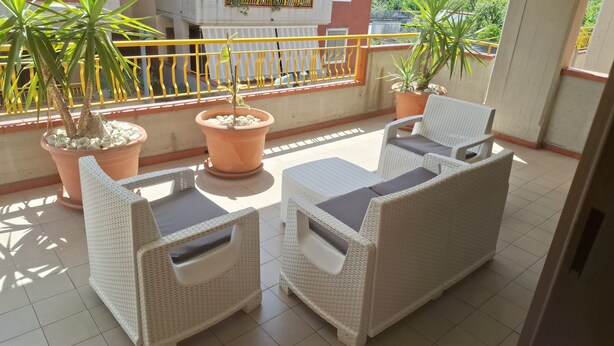 A balcony with two wicker sofas, a small table, and potted plants.
