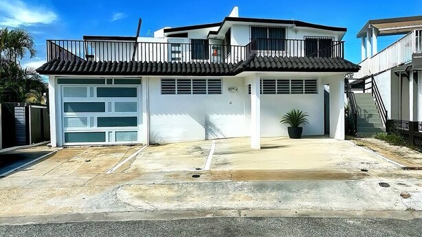 Ein zweistöckiges Haus mit Garage, Balkon und Treppe zu einem Obergeschoss.