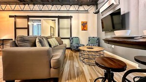 A modern living room with a sofa, two armchairs, a coffee table, and a TV.