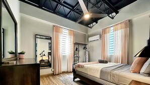A modern bedroom with a bed, bedside tables, a desk, a mirror, and an air conditioning unit. - Loft Living – Stylish & Central Santurce (San Juan)