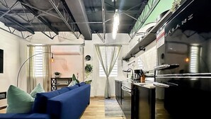 A compact living space with a kitchenette, a blue sofa, and a wooden floor. - Loft Living – Stylish & Central Santurce (San Juan)
