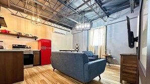 A modern kitchen with a red refrigerator, a blue sofa, and a wooden dining table. - Lofts @ Santurce – Your Urban Hideaway (San Juan)