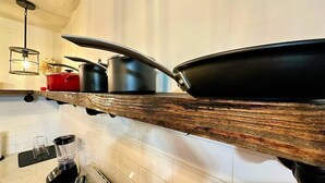 A kitchen with a wooden shelf holding pots and pans, a blender, and a coffee maker. - Lofts @ Santurce – Your Urban Hideaway (San Juan)