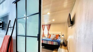 A modern bedroom with a bed, bedside table, lamp, and a sliding glass door leading to another room. - Santurce Skylight – Modern Lofts Stay (San Juan)