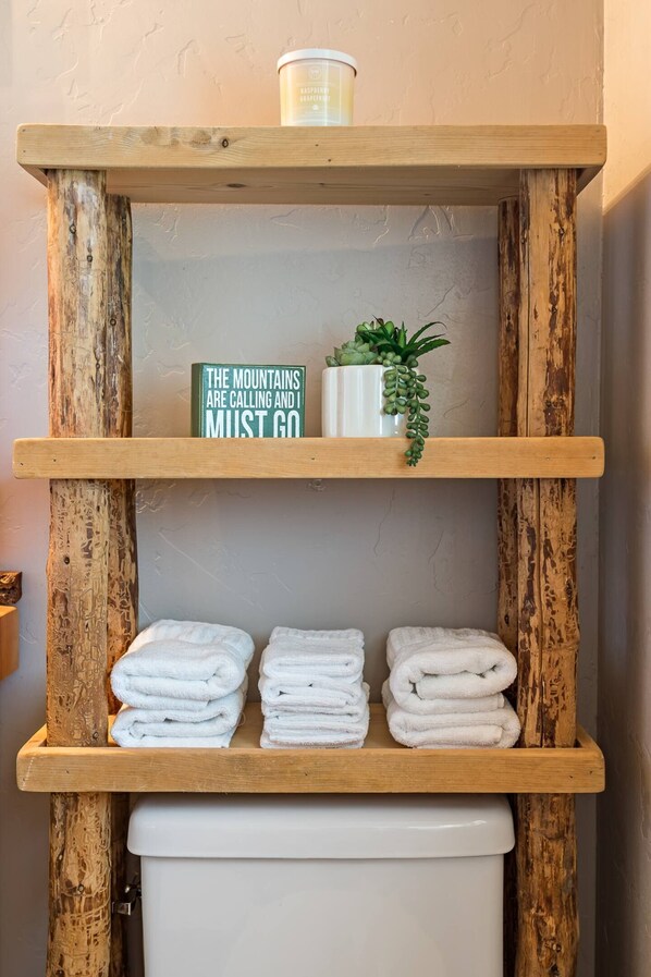 A wooden shelf with a sign, a potted plant, and folded towels. - Snoqualmie Pass Cabin: Hot Tub, Sauna, Hike & Ski (Snoqualmie Pass)