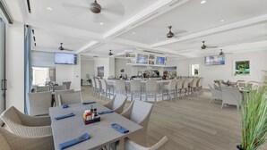 Ein geräumiger Essbereich mit hohen Decken, Deckenventilatoren und einer zentralen Bar mit Fernseher.