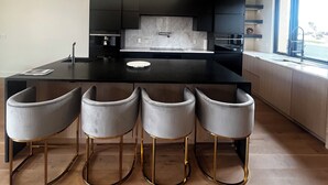 Cocina moderna con isla central, taburetes de bar y un amplio ventanal.