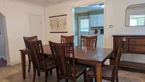 Ein Essbereich mit Holztisch und Stühlen, eine Küche im Hintergrund und ein Spiegel an der Wand.