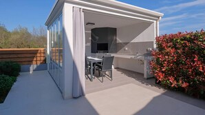A covered outdoor area with a grill, seating, and a TV. - Gorgeous home in Rebici (Rebici)