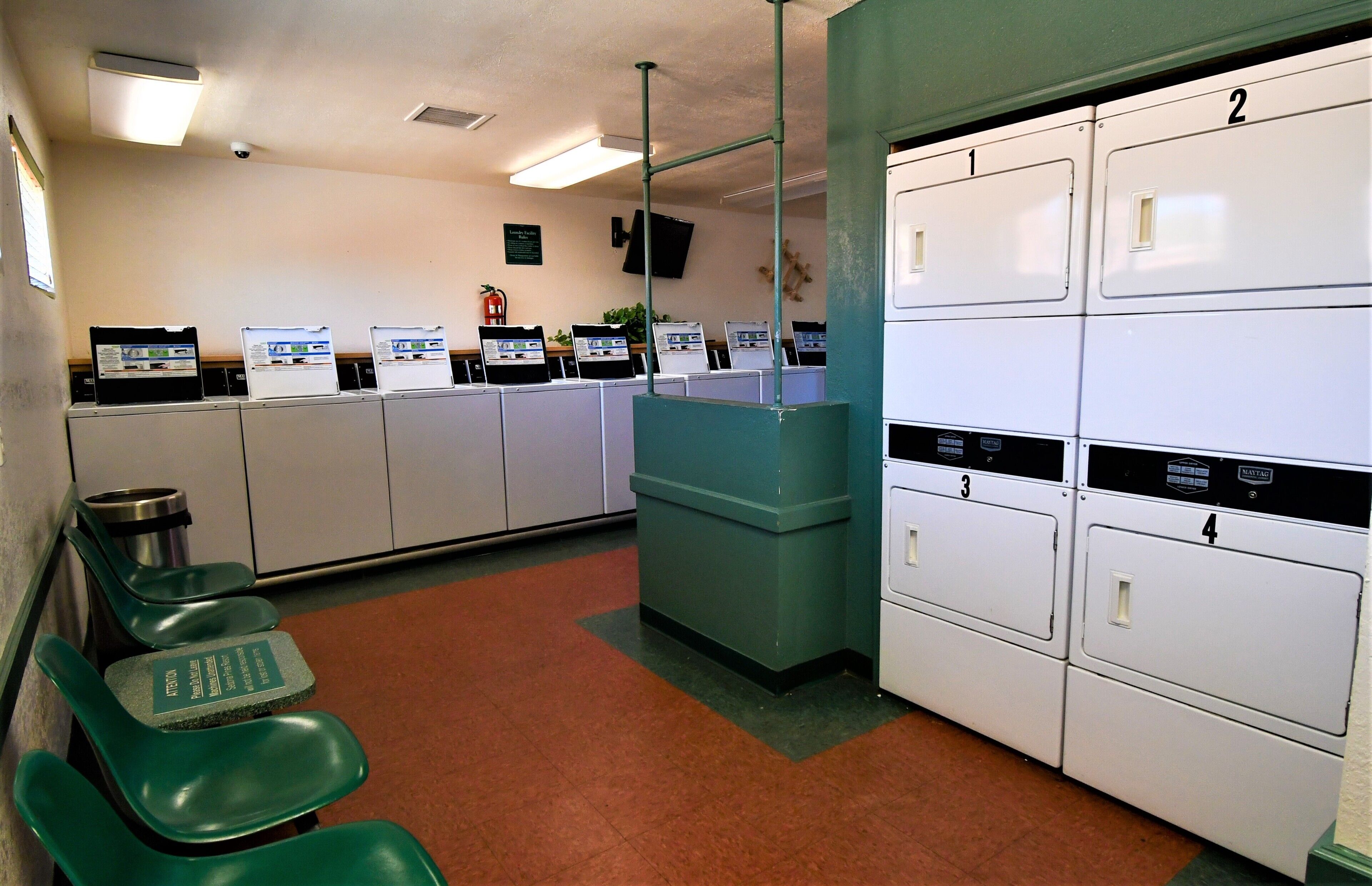 A waiting area with green chairs, a reception desk, and a row of white lockers numbered 1 to 4.