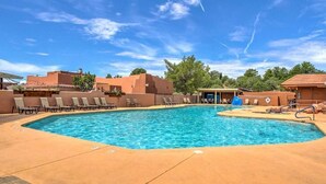 Une piscine avec des chaises longues et un petit bâtiment en arrière-plan.