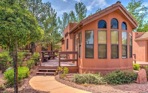 Una casa de un piso con techo curvo, ventanas grandes y un patio con mobiliario exterior.