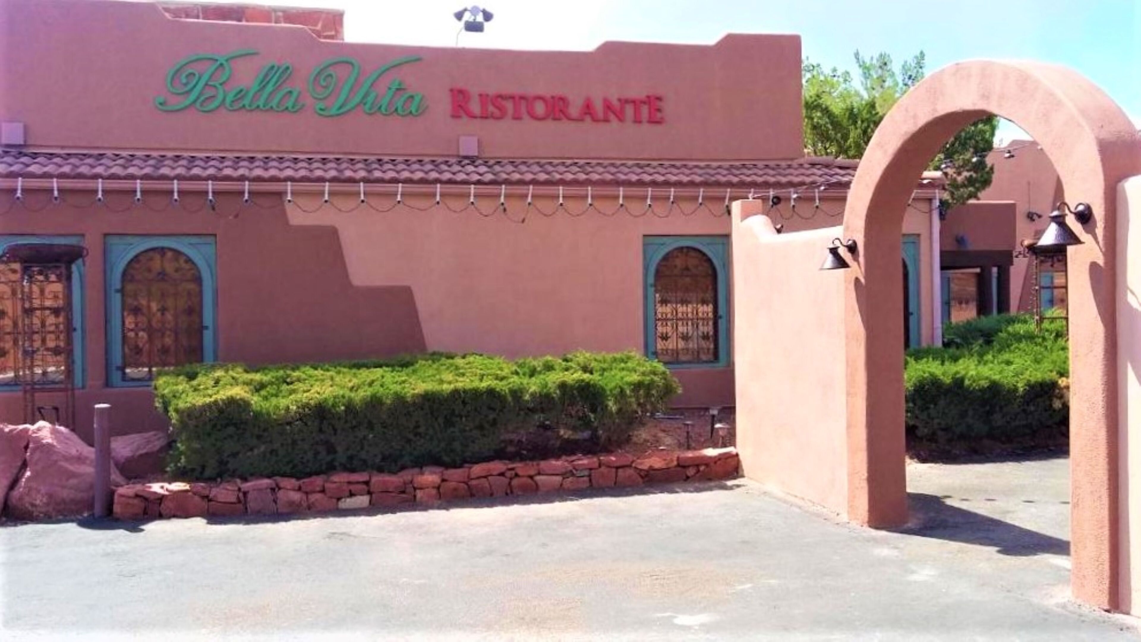 Um edifício com uma placa indicando "Bella Vita Ristorante" e um arco de pedra.