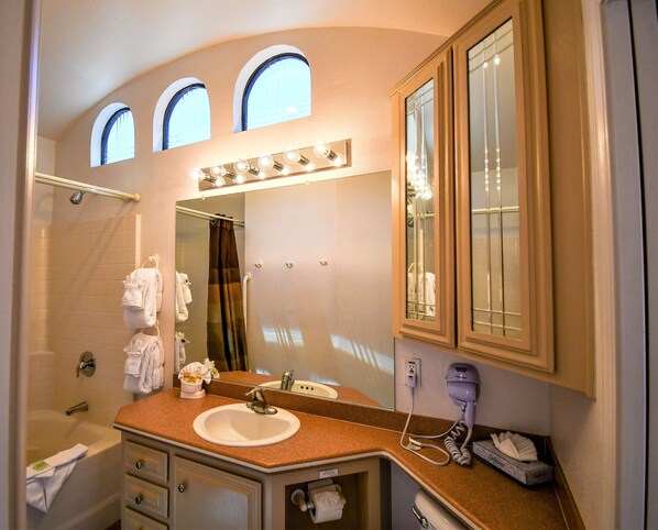 Une salle de bain équipée d’un lavabo, d’un miroir, d’un meuble-lavabo, d’un porte-serviettes, d’une douche et d’un sèche-cheveux.
