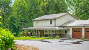 A two-story building with a covered porch, a garage, and a star decoration on the wall. - Pet-friendly, Stocked Fishing Pond, Hiking (Nineveh)