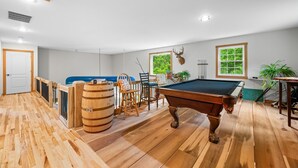 A wooden-floored room with a pool table, chairs, and a door. - Pet-friendly, Stocked Fishing Pond, Hiking (Nineveh)
