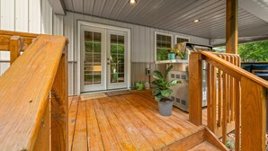 A wooden deck with a railing, a potted plant, and a kitchen area with a countertop and appliances. - Pet-friendly, Stocked Fishing Pond, Hiking (Nineveh)